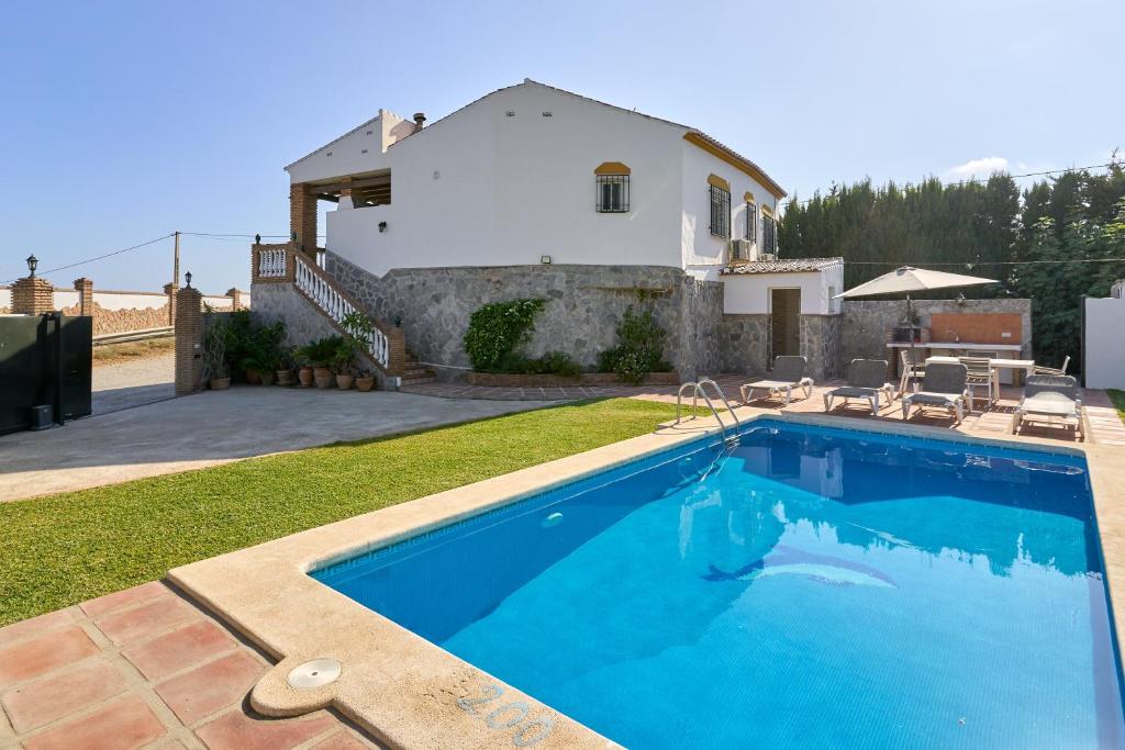 a swimming pool in front of a house at Villa El Peli in Nerja