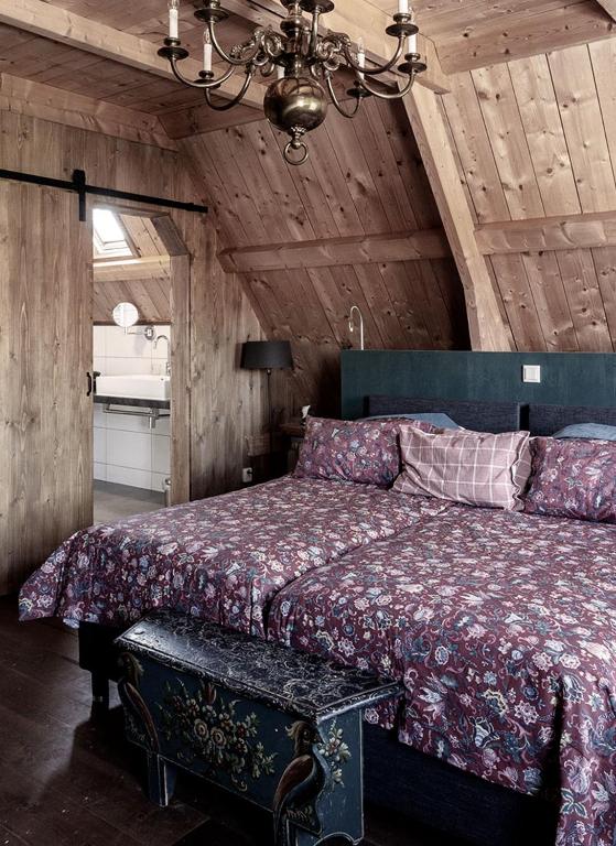 a bedroom with a large bed with a wooden ceiling at Hylper Huis in Hindeloopen