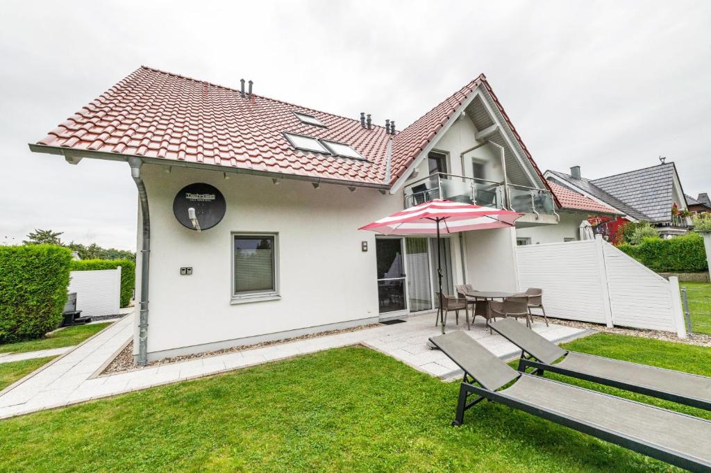 a house with a patio with a table and an umbrella at Domizil Eden - Erdgeschoss in Göhren-Lebbin
