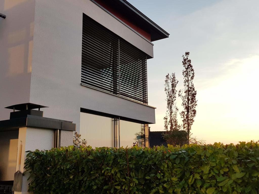 a white building with a window and a hedge at Ferienhaus mit Panoramablick in Bühlertal