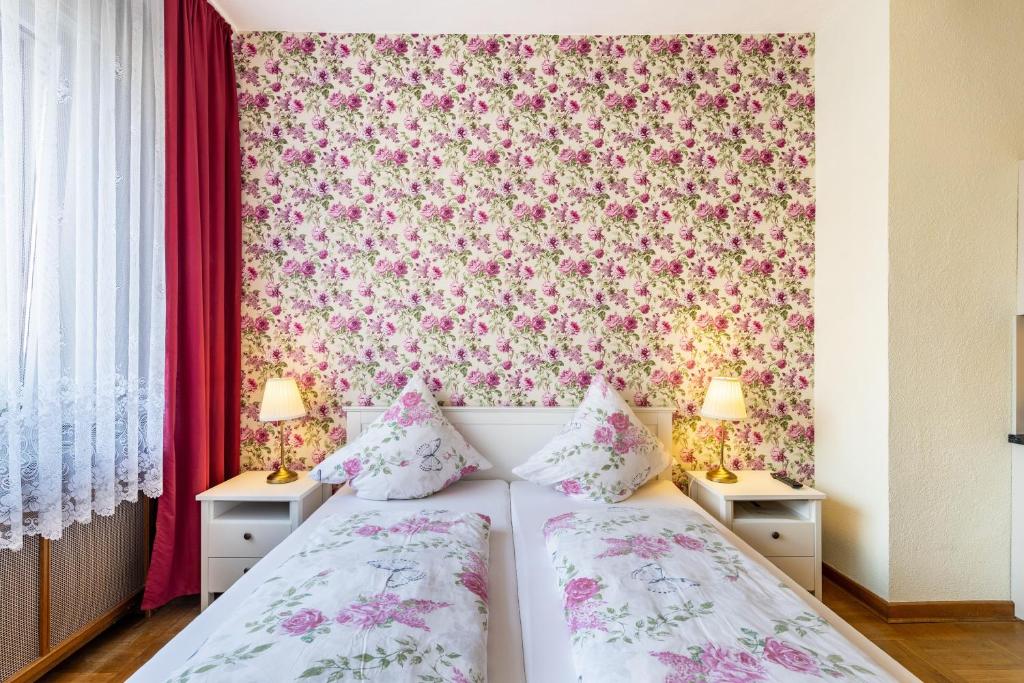 a bedroom with two beds and a floral wallpaper at Englisches Apartment in Kerken