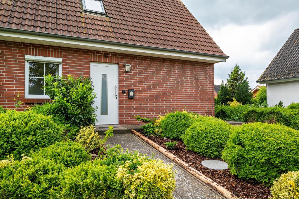 a brick house with a white door and some bushes at Ferienhaus Beckerwitz in Beckerwitz