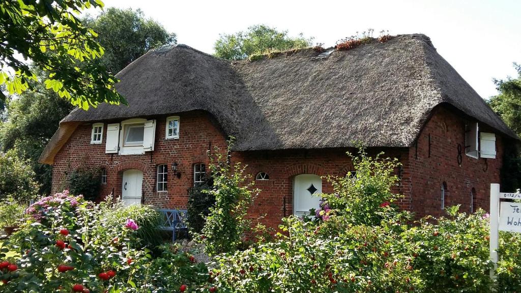 a red brick house with a thatched roof at Haus am alten Deich in Rodenäs