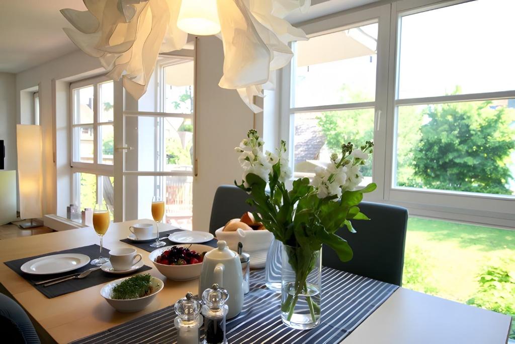 a dining room table with a vase of flowers on it at Komfort-Ferienwohnung am See in Bodman-Ludwigshafen
