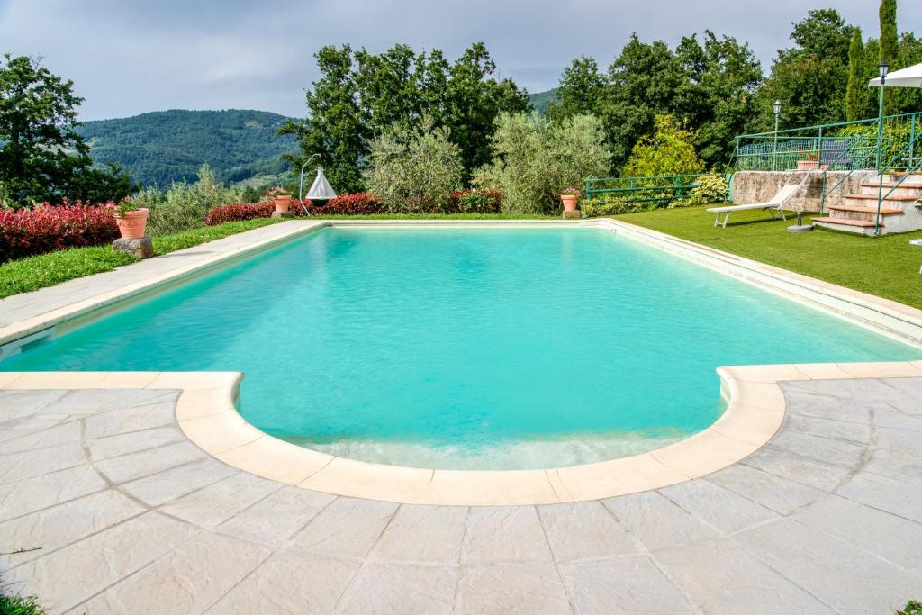 a swimming pool with blue water in a yard at Il Cerro Appartamento Basic per due in Pelago