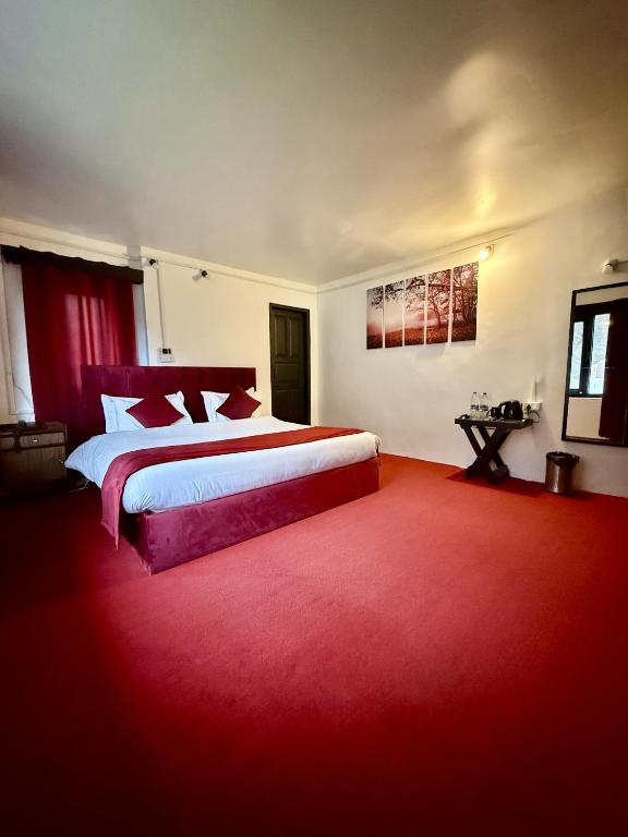 a bedroom with a large bed and a red carpet at Riverdale by Stay Pattern in Pahalgām