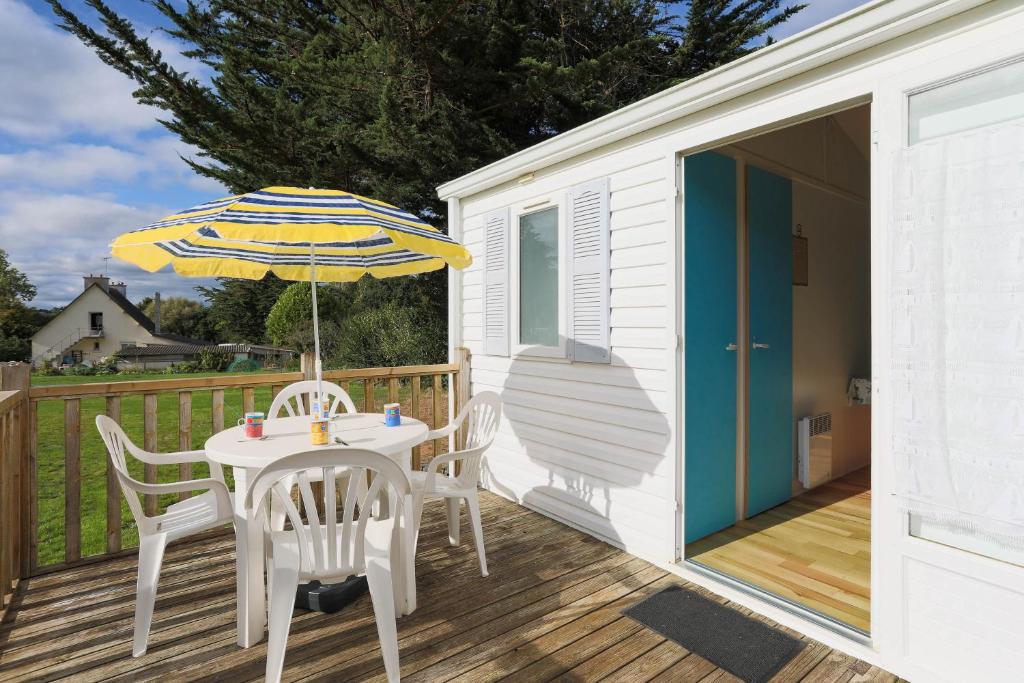 a table and chairs with an umbrella on a deck at Mobil home 2 Bikini in Plouha