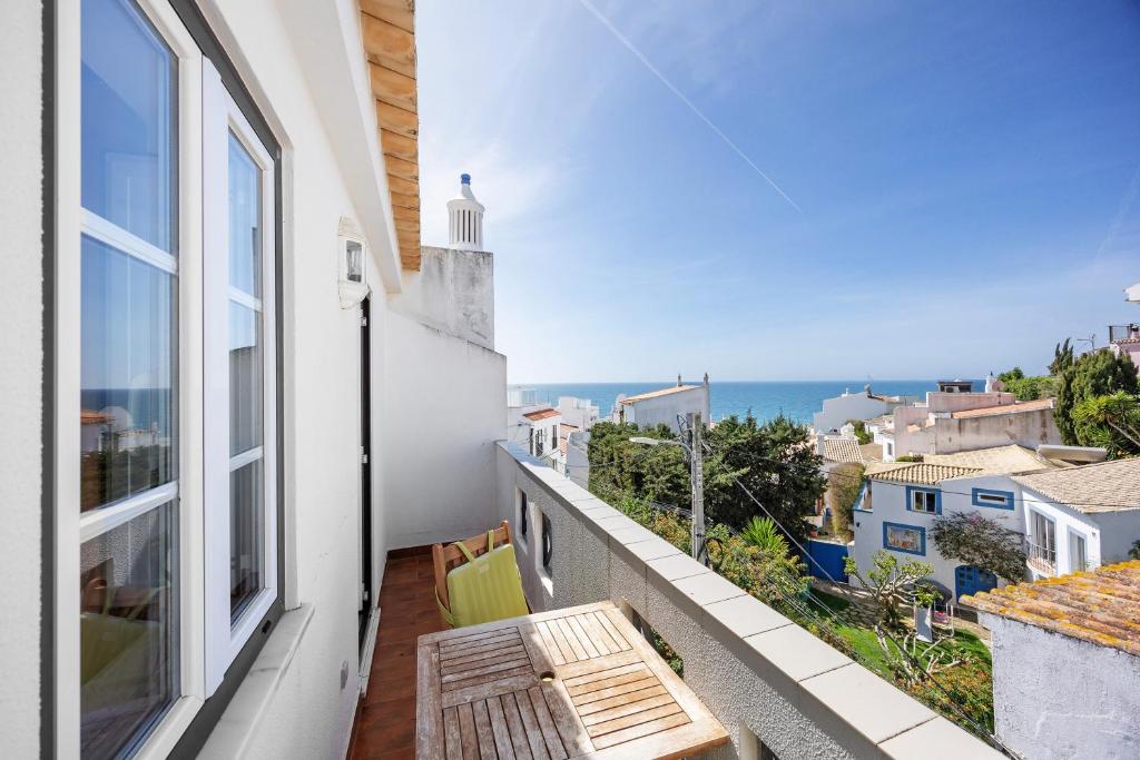a balcony with a bench and a view of the ocean at Burgau - A Casa dos Avós in Burgau