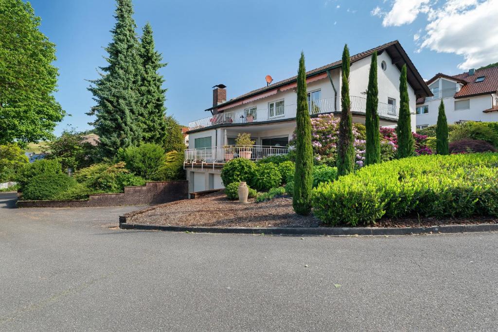 a house with trees and bushes in front of a street at Ferien Am Weinberg in Kappelrodeck