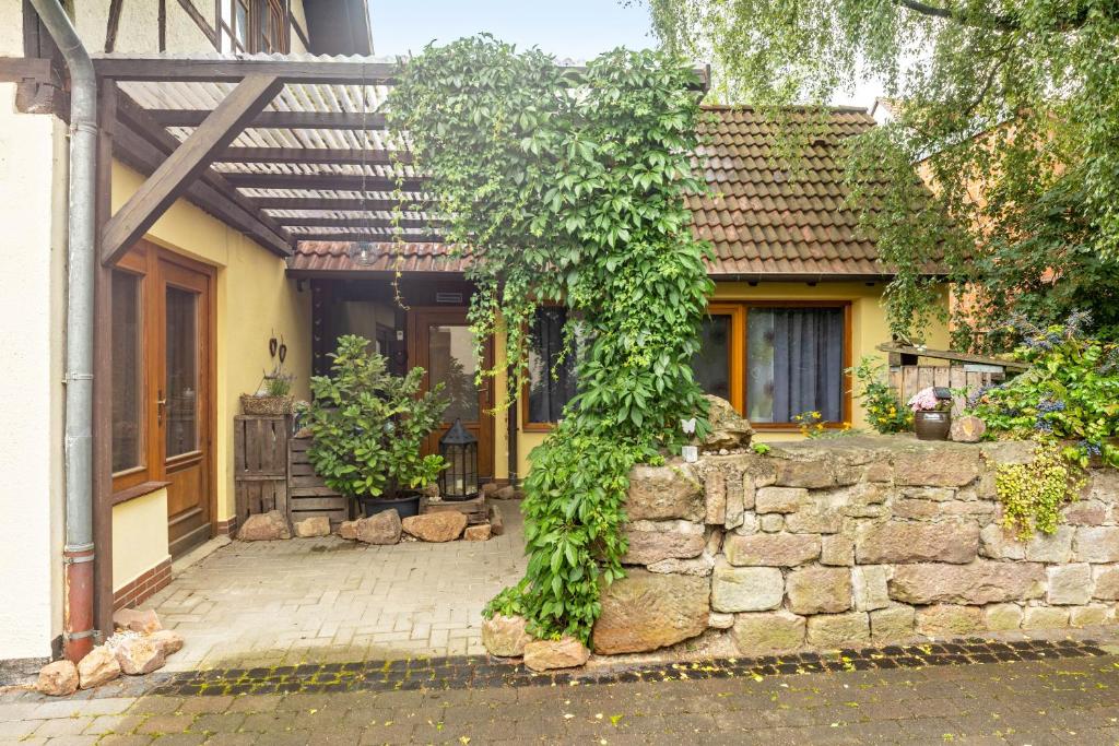 a house with a stone wall and a tree at 1 Zimmer Ferienwohnung in Lohfelden