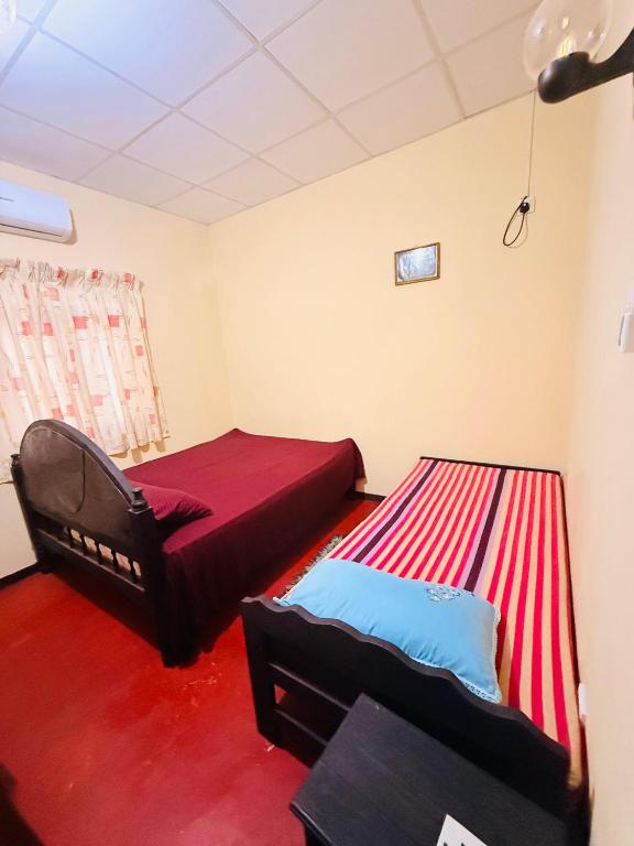 two beds in a room with a red carpet at C&C Holiday Home in Nikawatawana