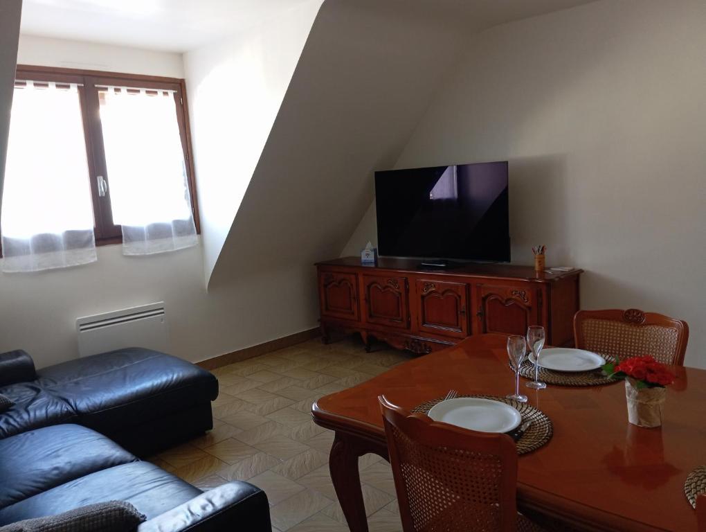 un soggiorno con un tavolo e una TV di Gîte Le Lot a Espalion