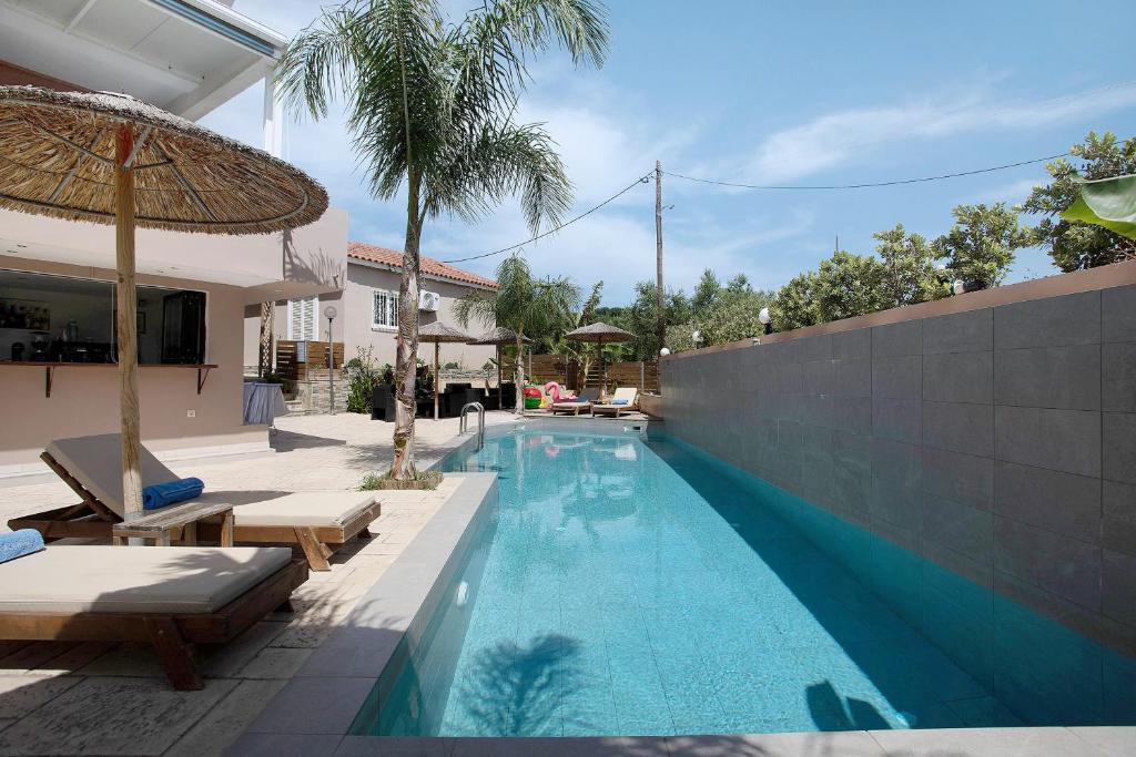a swimming pool with two lounge chairs and an umbrella at Villa Dionysia Studio S5 in Alikanas