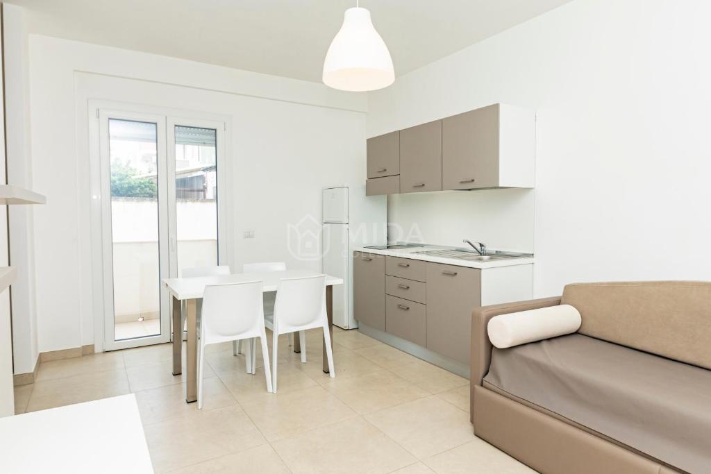a kitchen and living room with a table and a couch at Ungaretti Resort in Porto Cesareo