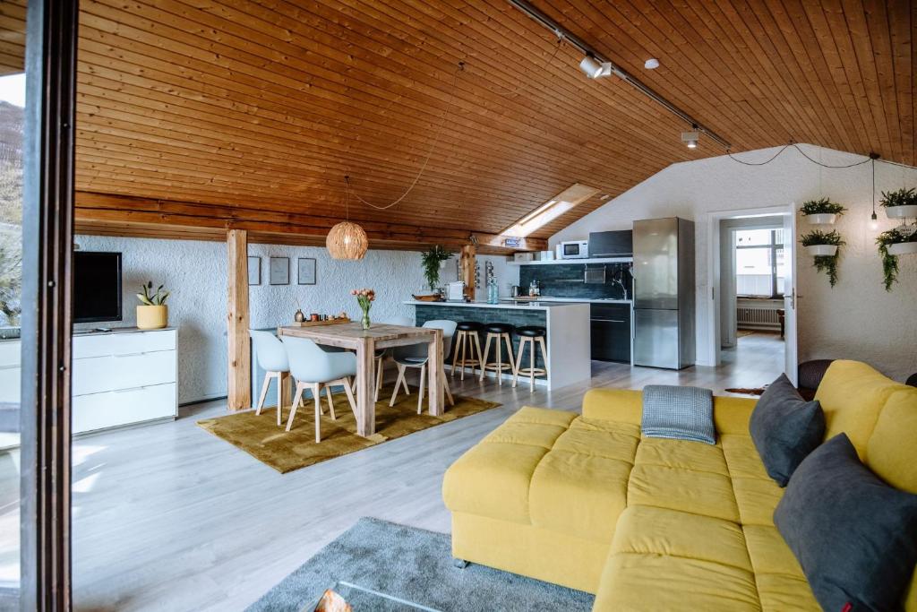 a living room with a yellow couch and a kitchen at Ferienwohnung Seeidyll am Wörthsee in Wörthsee