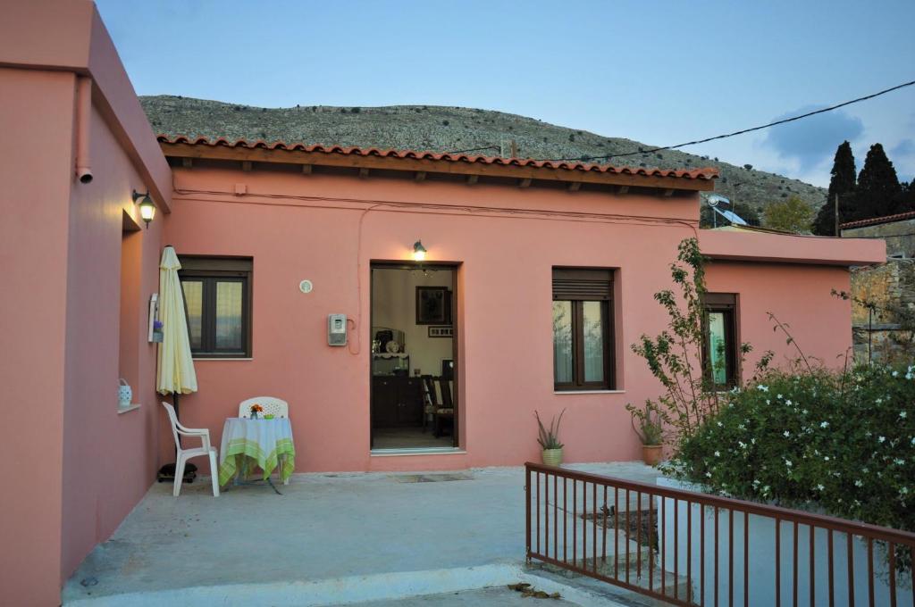 a pink house with a patio and a table and chairs at House For Rent In Apostolous in Apóstoloi