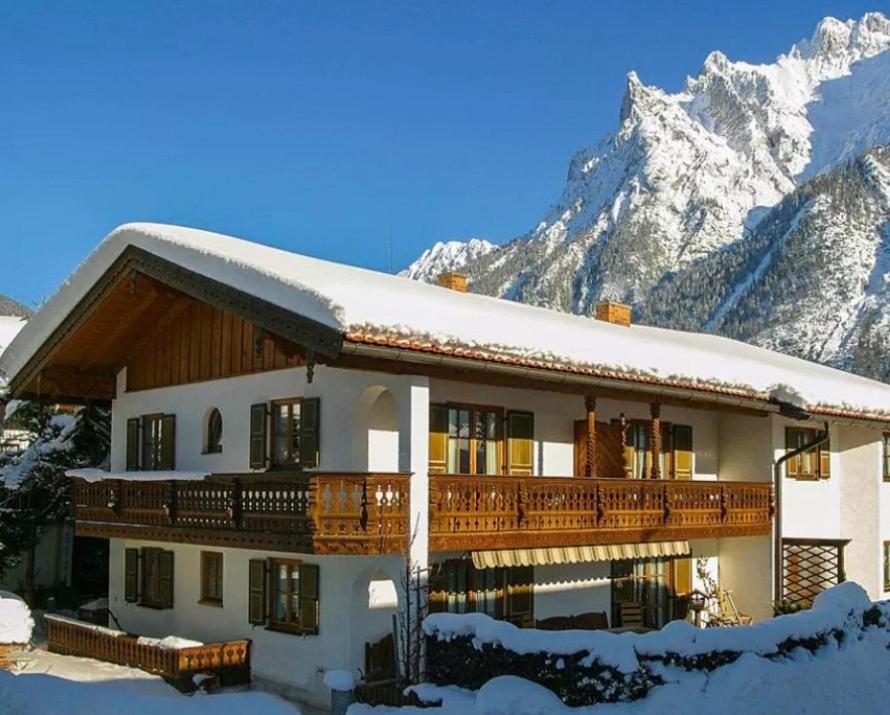 a building with snow covered mountains in the background at Haus Verena Mittenwald in Mittenwald