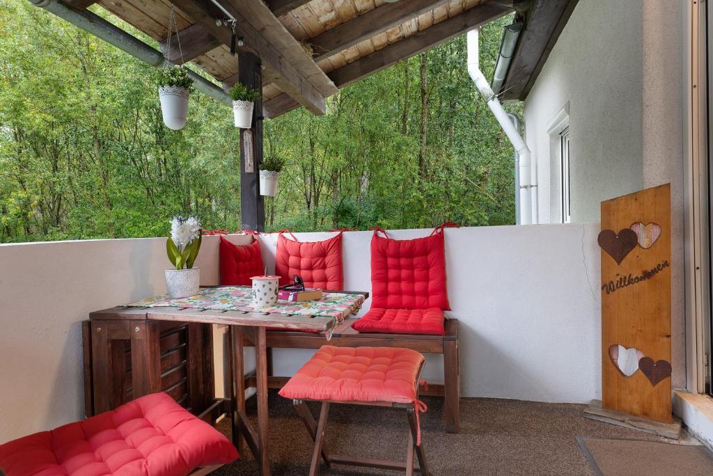 a patio with a table and red cushioned chairs at Im Grünen in Weil der Stadt