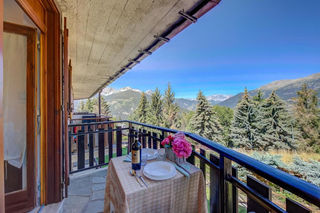 a table with a bottle of wine and flowers on a balcony at Studio La Borracina Mountain View - Happy Rentals in Sauze dʼOulx