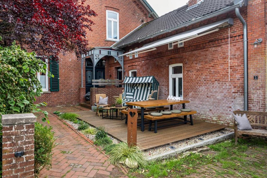 a wooden deck with chairs and a table in front of a brick building at Ferienwohnung Flut am Weserstrand in Sandstedt