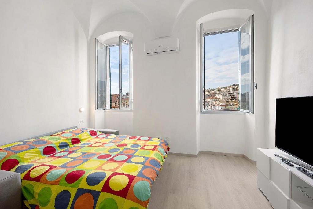 a bedroom with a colorful bed and two windows at Domus Madonnina in Sanremo