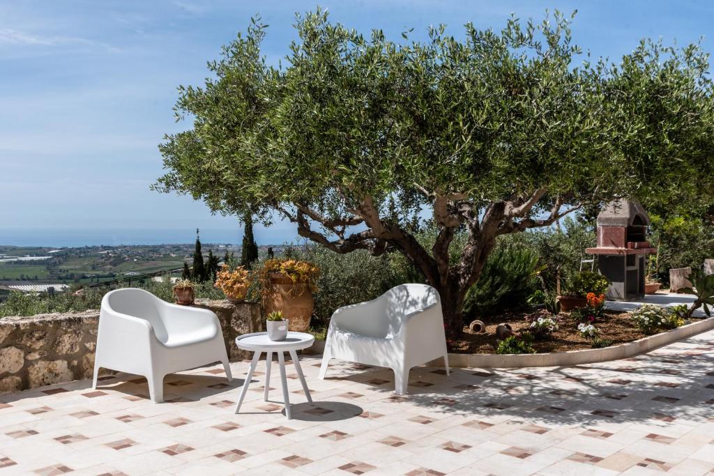 two white chairs and a table under a tree at Villa Simona con giardino in Favara