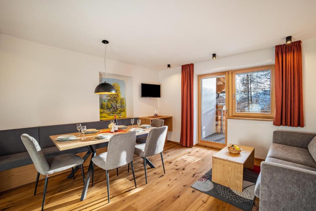 a dining room and living room with a table and chairs at App Hubertus - Moosstock in Sand in Taufers
