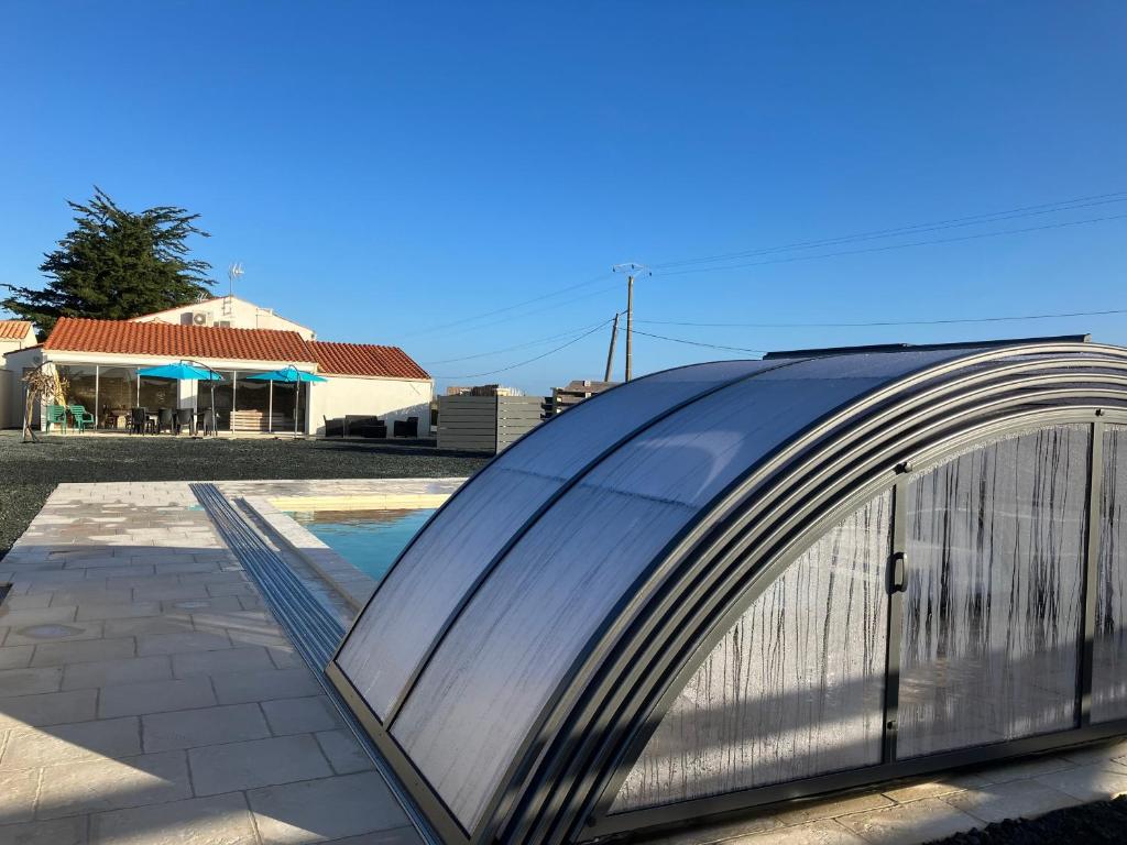 a curved metal building with a pool in front of a house at Gîte les 2 Fontaines in Marans