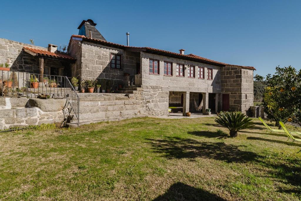 a stone house with a yard in front of it at Cantinho da Tilde in Fafe