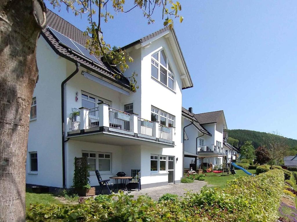 a white building with a balcony and a table at Ferienwohnung Am Kamp in Schmallenberg
