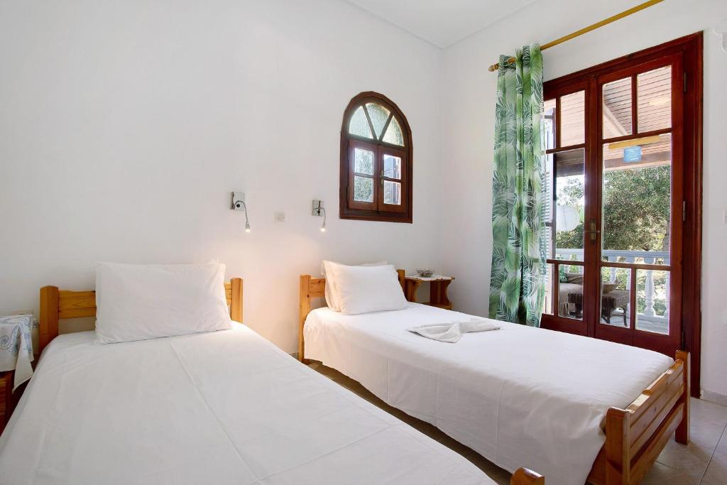 two beds in a room with a window at Areti Orfeas Apartment 6 in Vasilikos