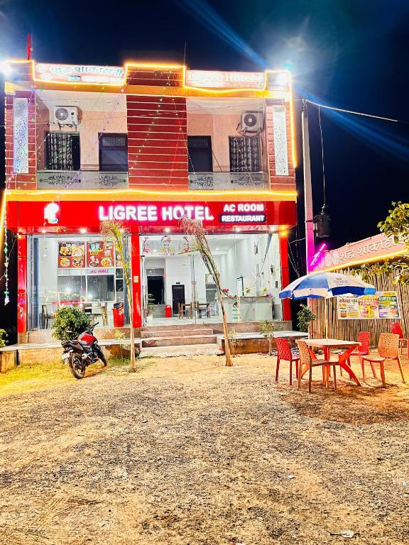 a hotel with tables and umbrellas in front of a building at Ligree Hotel and Restaurant in Jatwāra