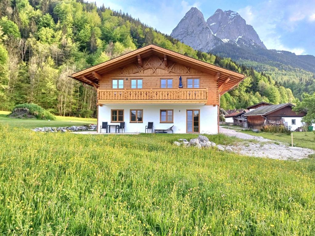 a house in a field with a mountain in the background at Ferienwohnung Alpenveilchen in Grainau