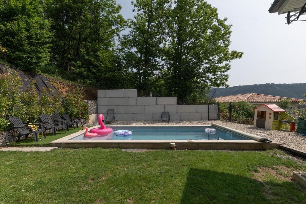 a swimming pool with a pink toy in the grass at Gîte les Monteils in Vesseaux