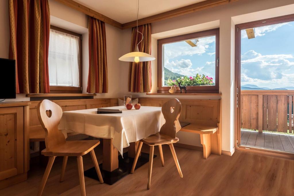 a dining room with a table and chairs and windows at Kristiania Apartement Typ A1 in Siusi