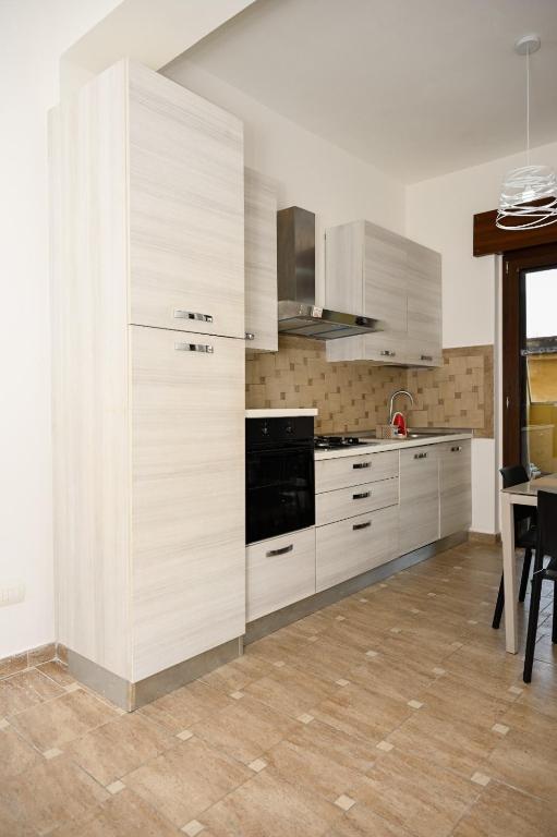 a kitchen with white cabinets and a black appliance at La casetta di Claudia in Nettuno