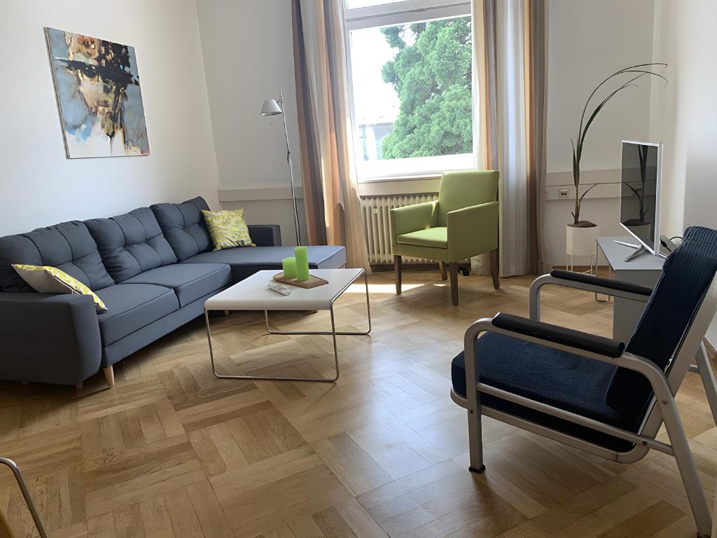 a living room with a blue couch and chairs at Bodenseeloft H E 66 in Kressbronn am Bodensee