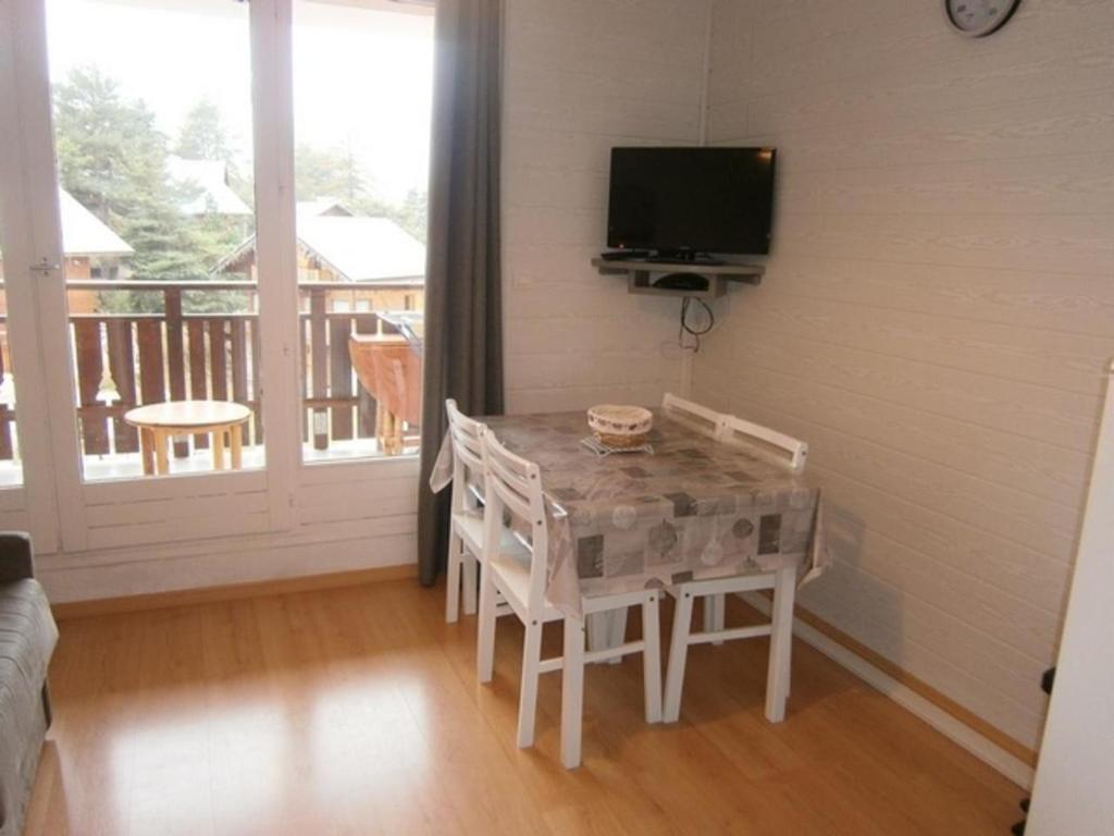 a dining room with a table and chairs and a television at Studio Les Fontettes 2 in Le Dévoluy