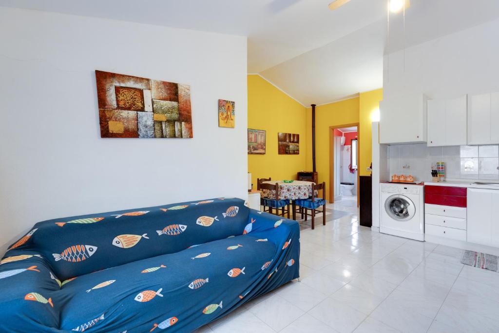 a living room with a blue couch and a kitchen at Home Holidays Pintadera 2 in Bosa