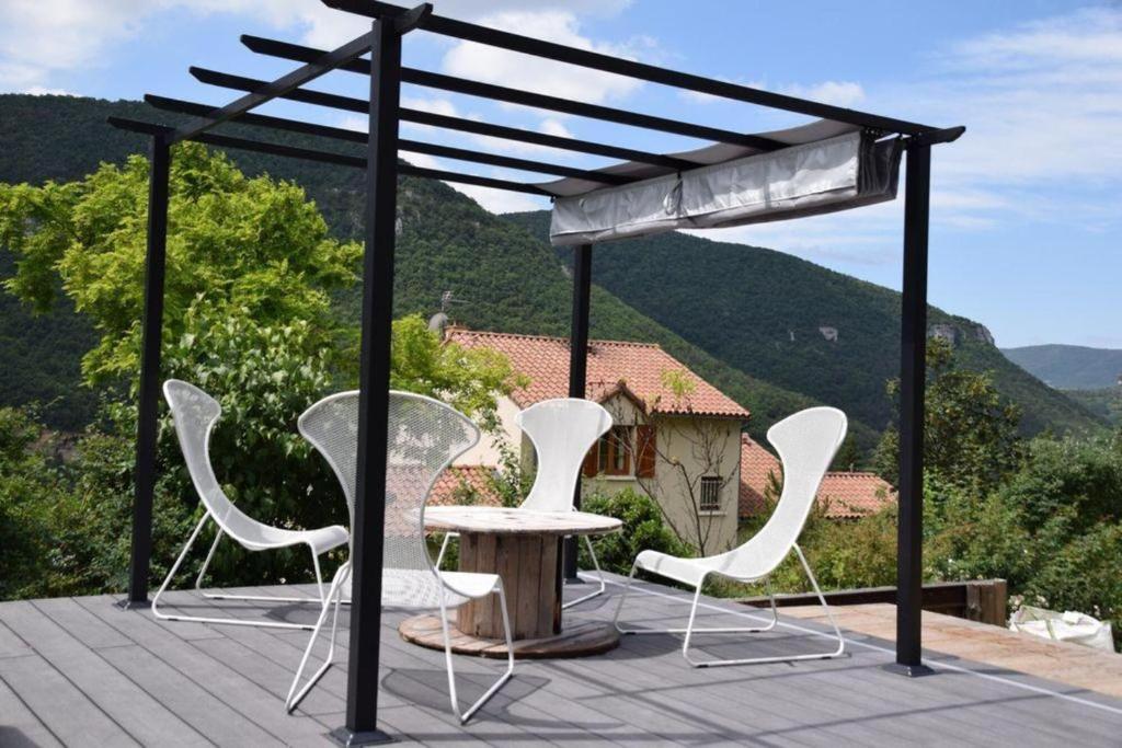 a group of chairs and a table on a deck at Cocoon,Vue Montagne,Jacuzzi privé in Mostuéjouls