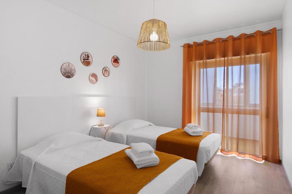 a bedroom with two beds and a window and a chandelier at Justo's House in Faro