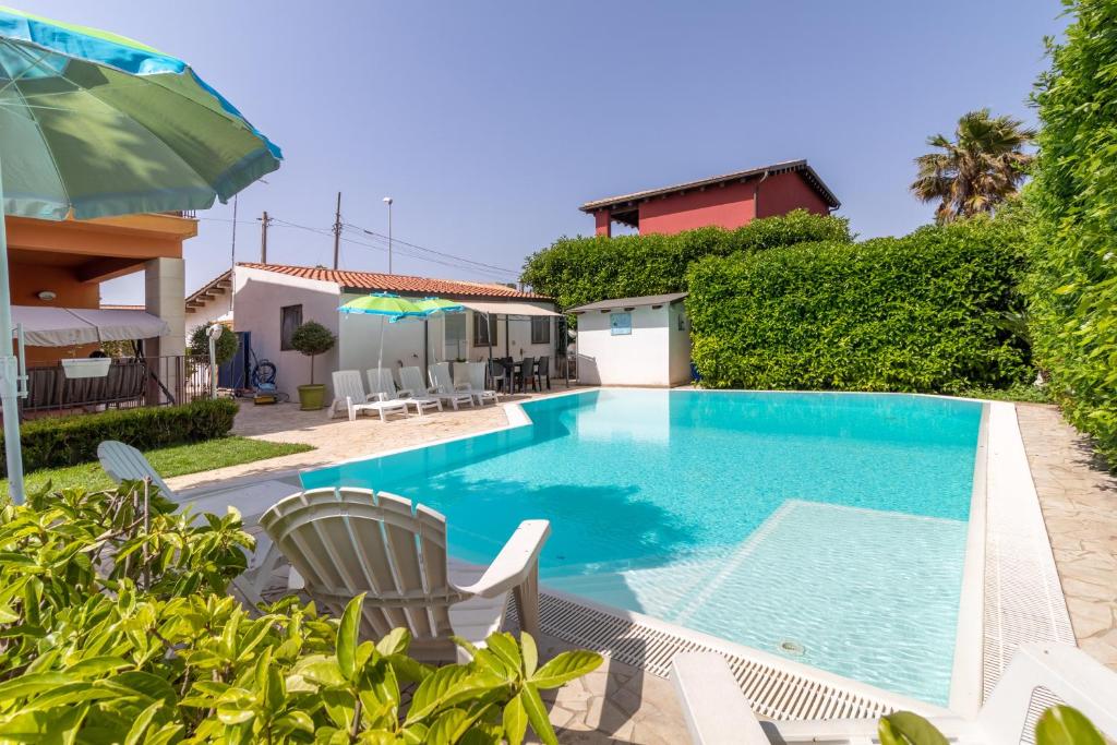 a swimming pool with chairs and a house at Villa Arianna in Ragusa