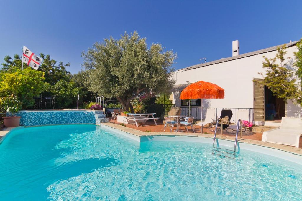 a swimming pool with an umbrella and a table and chairs at Casa Ginepro in Quartu SantʼElena