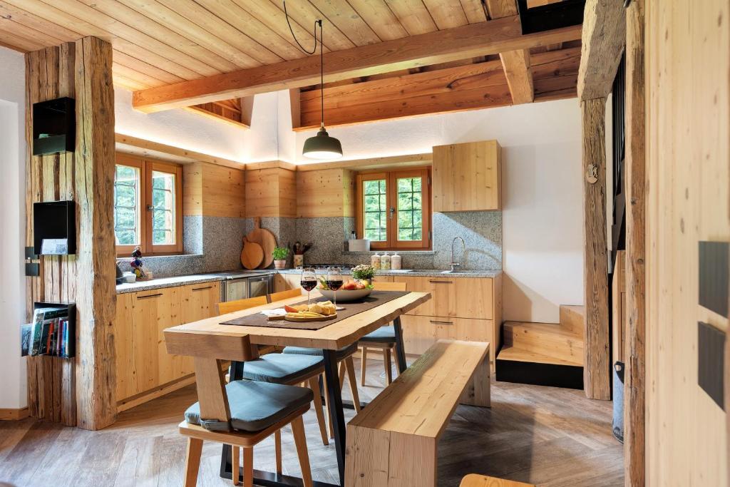 a kitchen with wooden cabinets and a wooden table and chairs at Baita Valon - Alpine Hideaway in Comano Terme