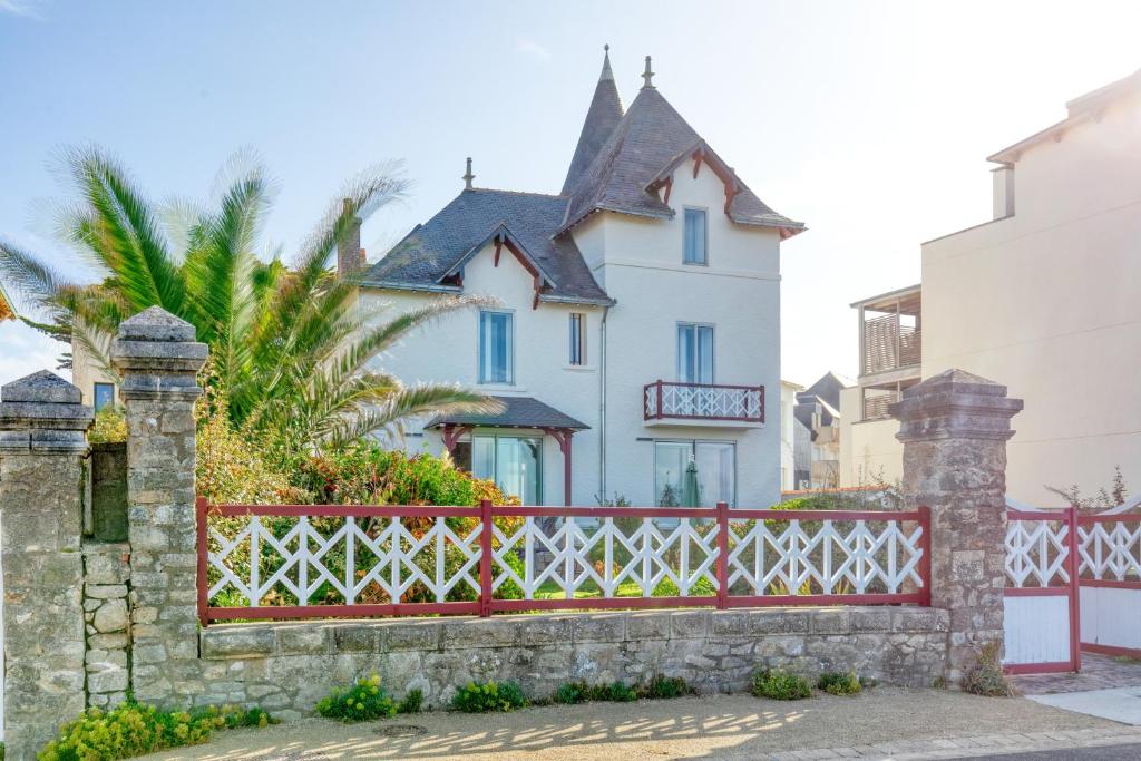a white house with a red fence at Villa Lin et Maree face océan in Le Croisic