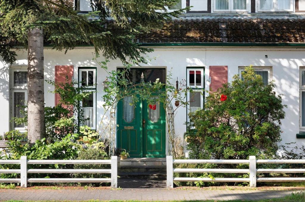 a white house with a green door and a white fence at Die Kleine Ferienwohnung in Schneverdingen