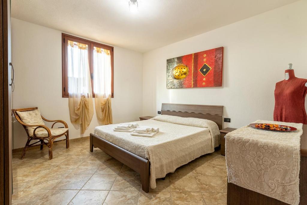 a bedroom with two beds and a chair in it at Casa Vacanze vicino ad alghero in Olmedo
