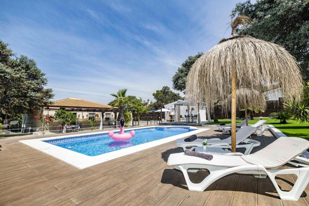 a swimming pool with two lounge chairs and an umbrella at Villa mis Raices in Castilblanco de los Arroyos