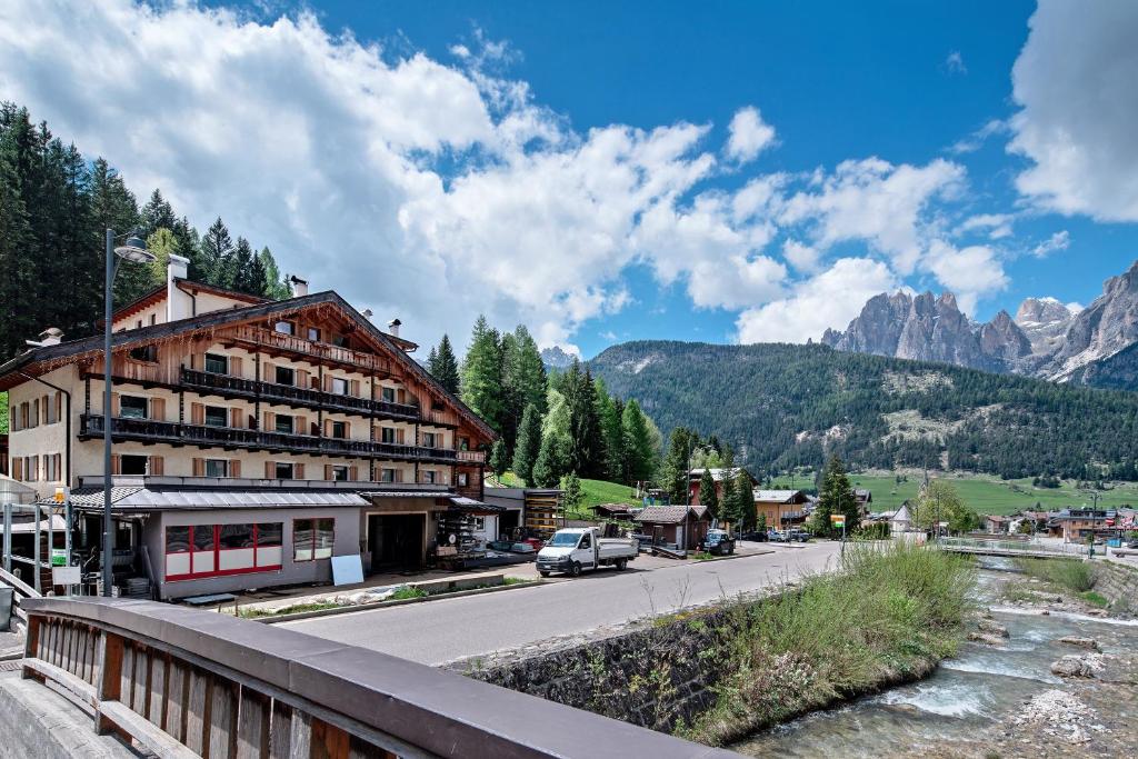 a building on a street with mountains in the background at Ciasa Badia in Pozza di Fassa