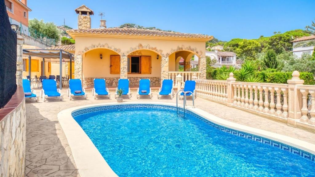 a villa with a swimming pool and blue chairs at Costacabana - Villa Sarai in Lloret de Mar